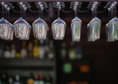 Close-up of cocktail glasses hanging upside down with blurred bar background.
