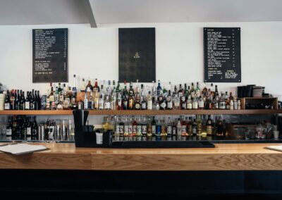 A modern bar counter displaying a wide variety of alcohol bottles on shelves, suitable for restaurant and business themes.